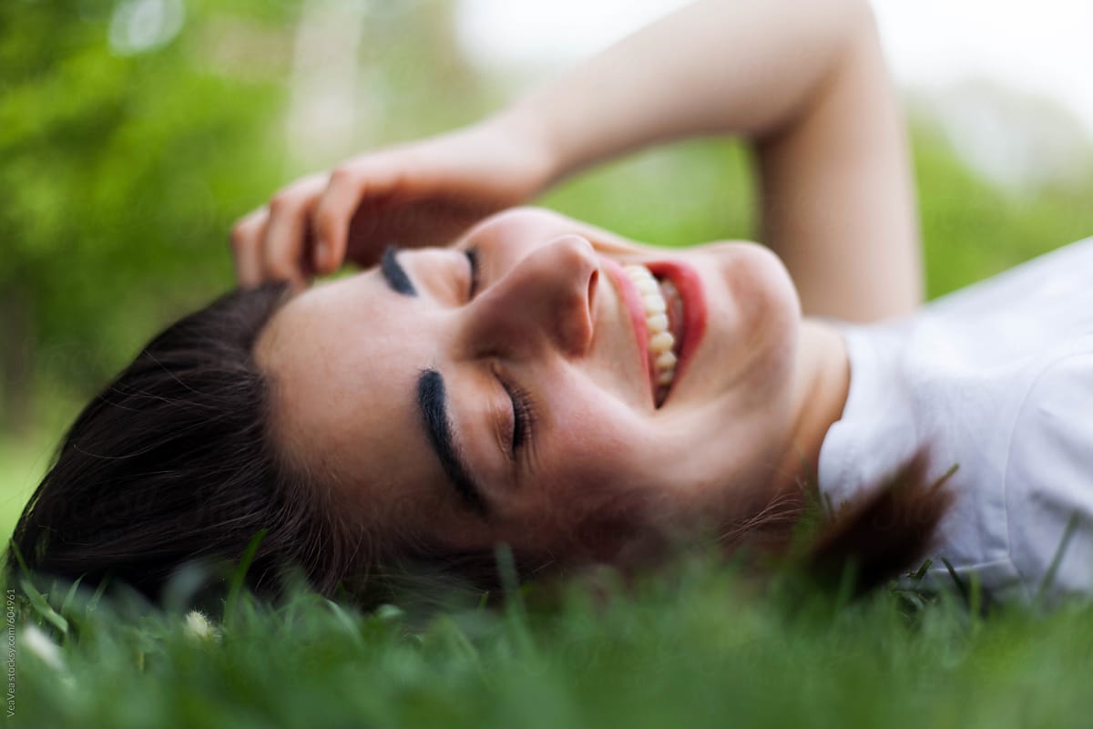 Young Beautiful Woman Smiling Lying On Grass By Stocksy Contributor