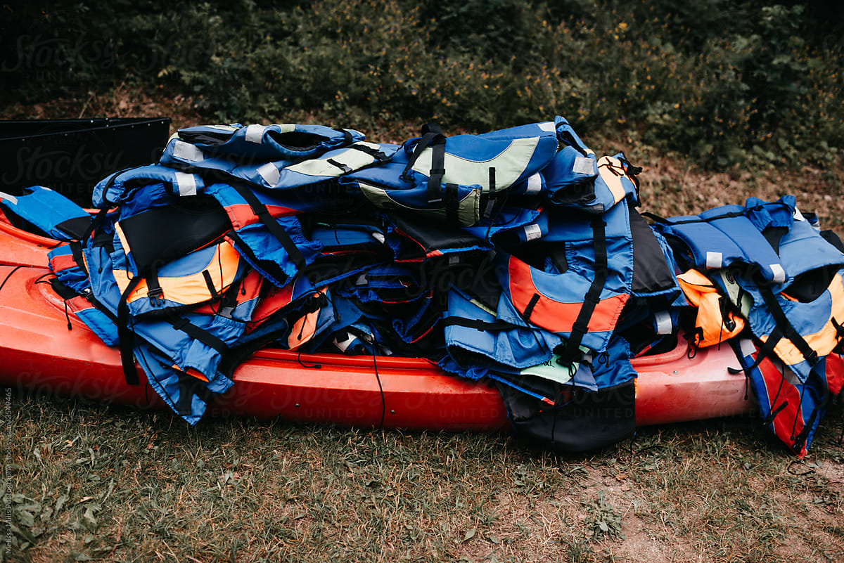 Red canoe with a bunch of life jackets stacked on top