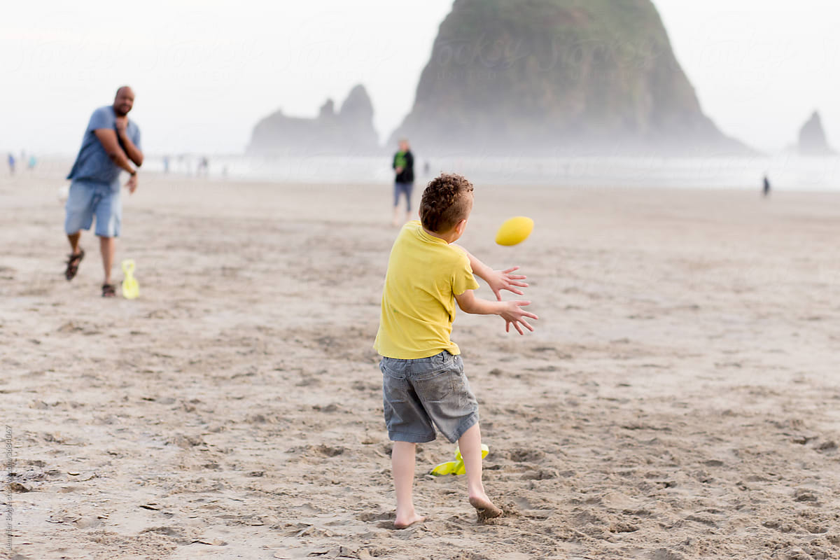 Boy attempts to catch football on beach