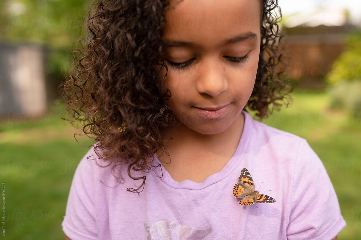 Girl cautiously glances down at butterfly on her chest