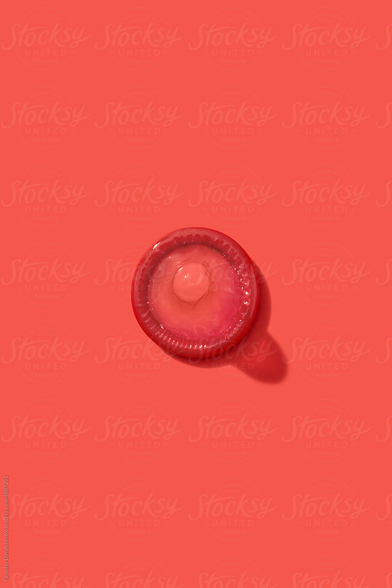 One condom on red background.