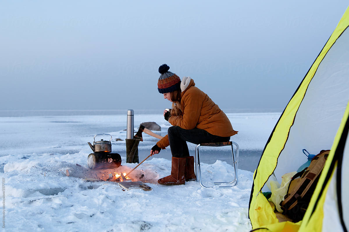 Woman near campfire and tent on winter day