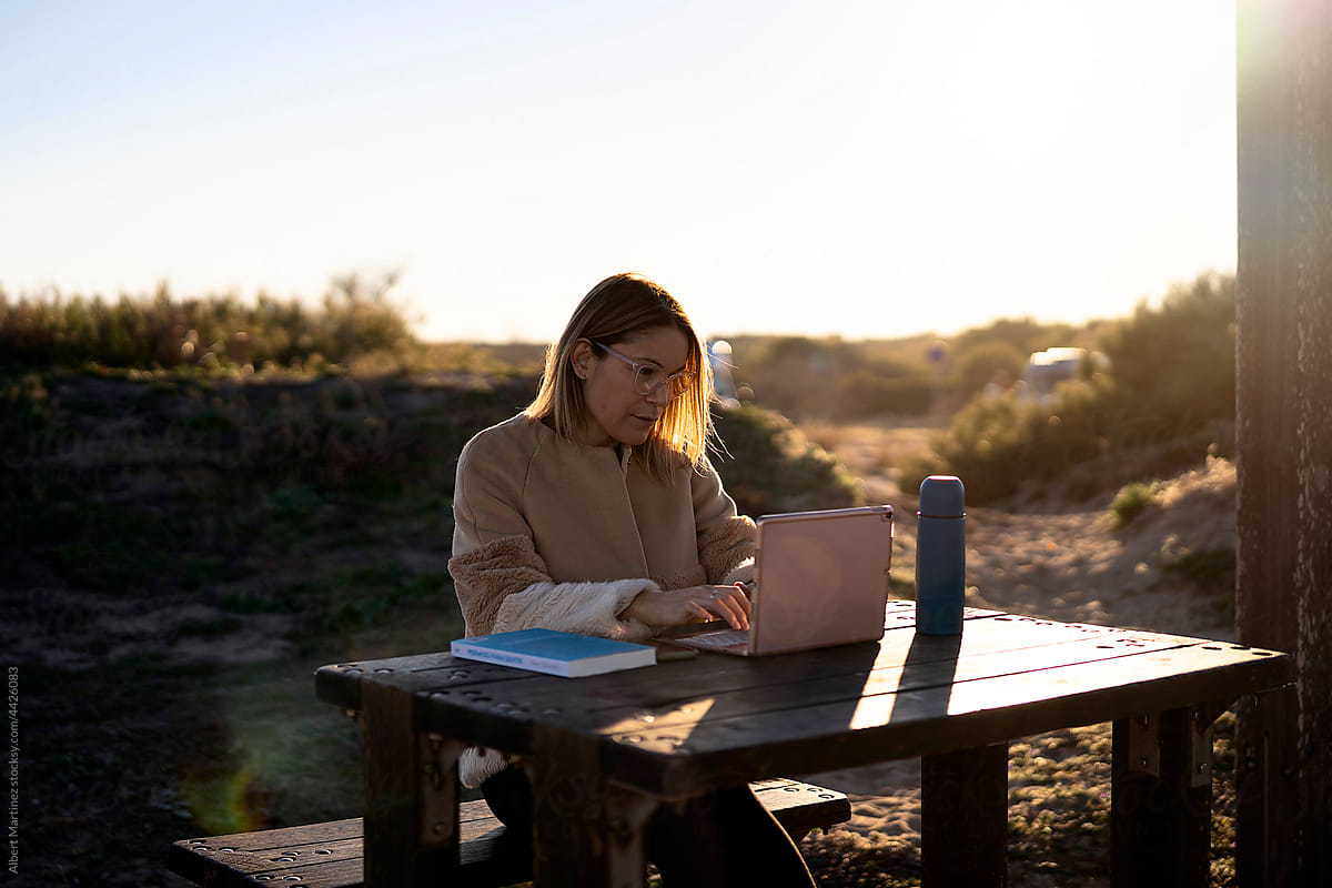 Serious woman browsing laptop in countryside