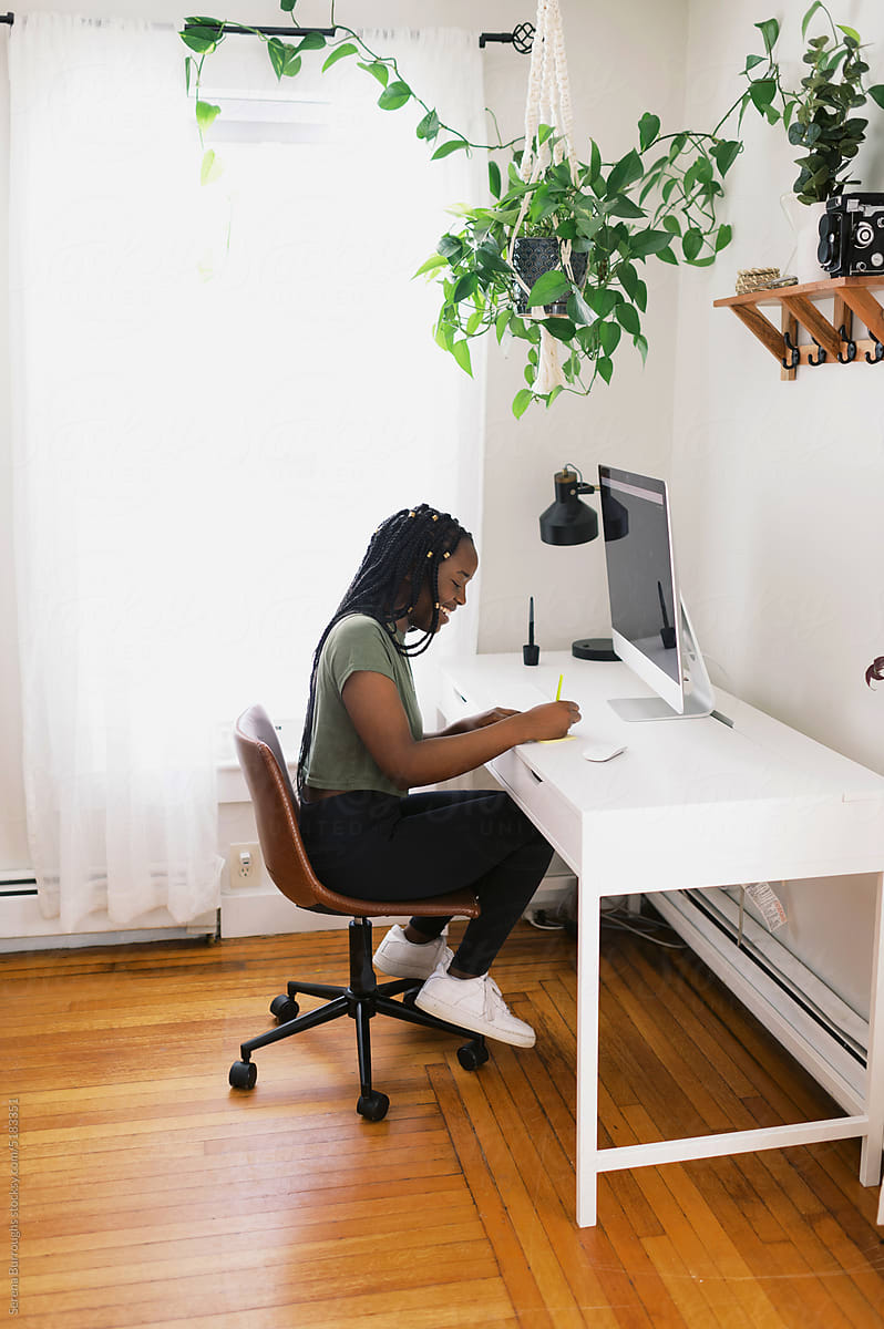 Smiling black woman working at desk in her home