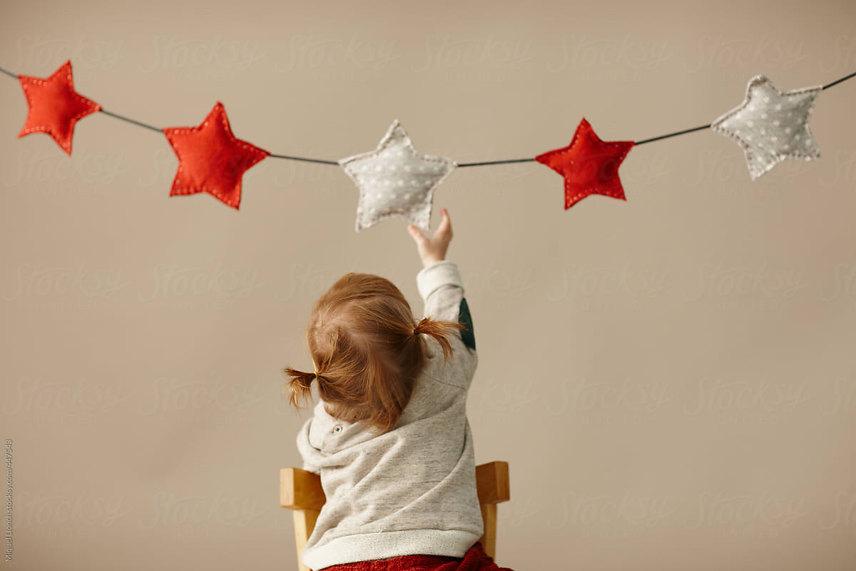 Little girl trying to reach a hanging Christmas star