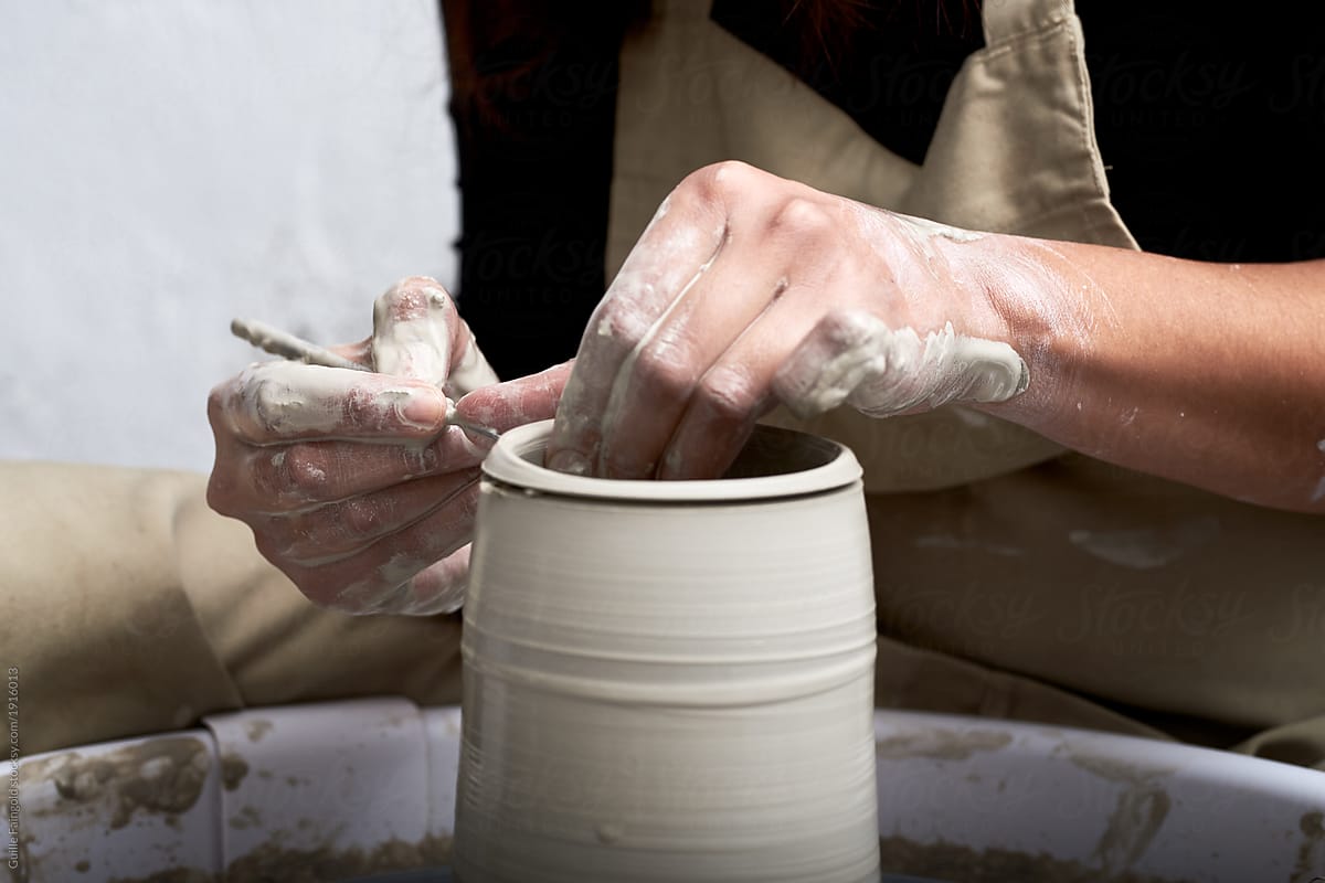Sculptor decorating the clay vase on pottery wheel.