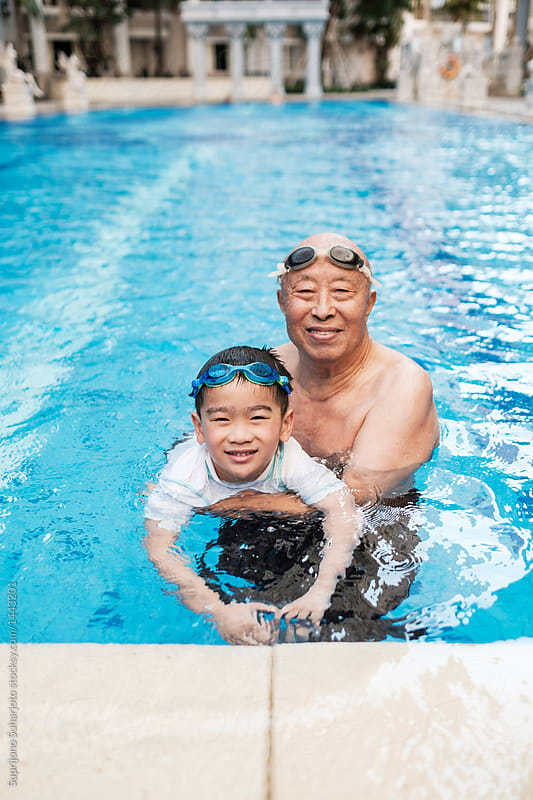 Asian Grandfather Playing With Grandson in the Swimming Pool