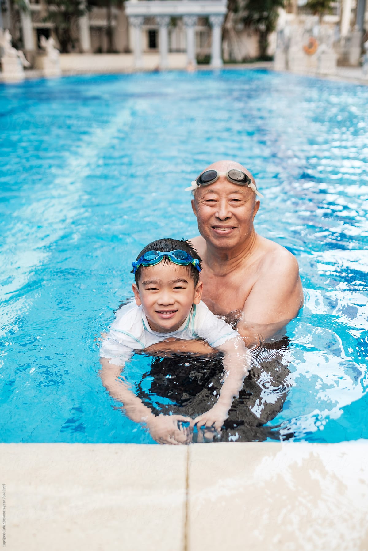 Asian Grandfather Playing With Grandson in the Swimming Pool
