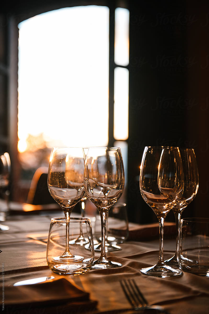 Glasses of white wine illuminated by the evening sun in a fancy Italian restaurant