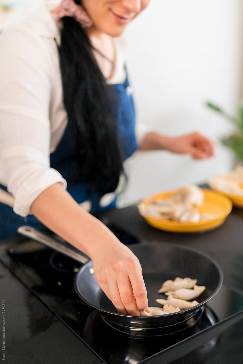 Crop Japanese woman cooking gyoza in kitchen