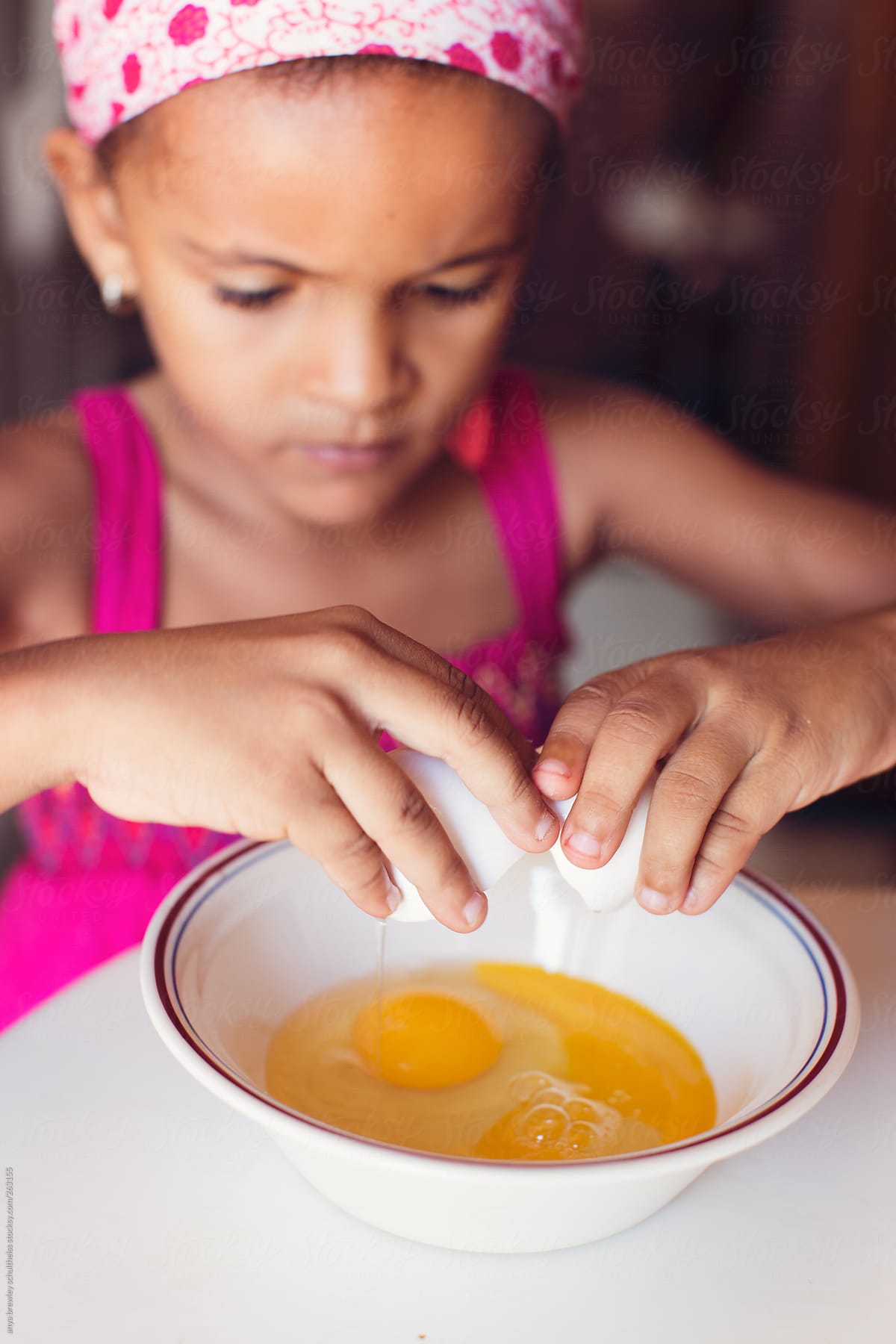 Young girl cracking eggs into a bowl