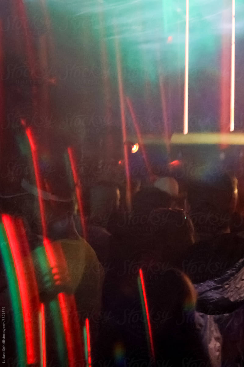 Crowd of anonymous people at club and neon lights in dark environmet