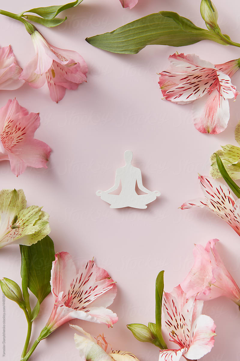 Paper figure meditating inside circle made of flowers