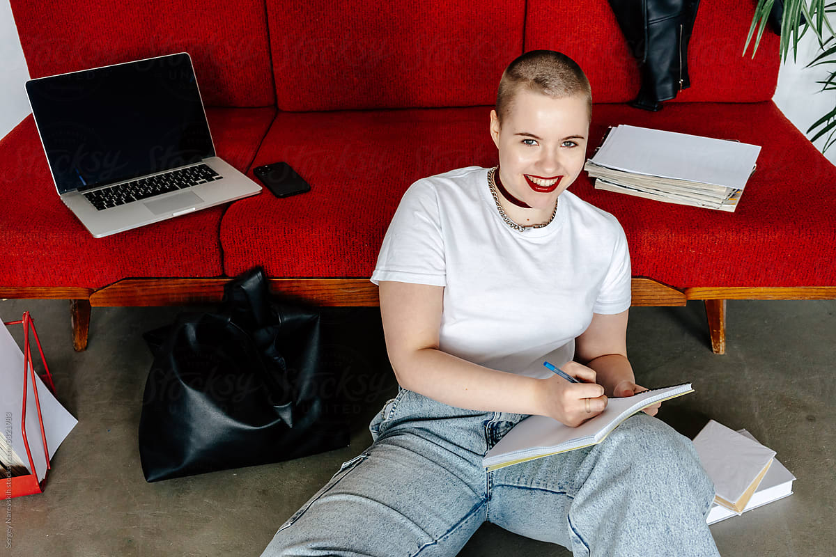 Millennial female doing homework at home sitting at floor