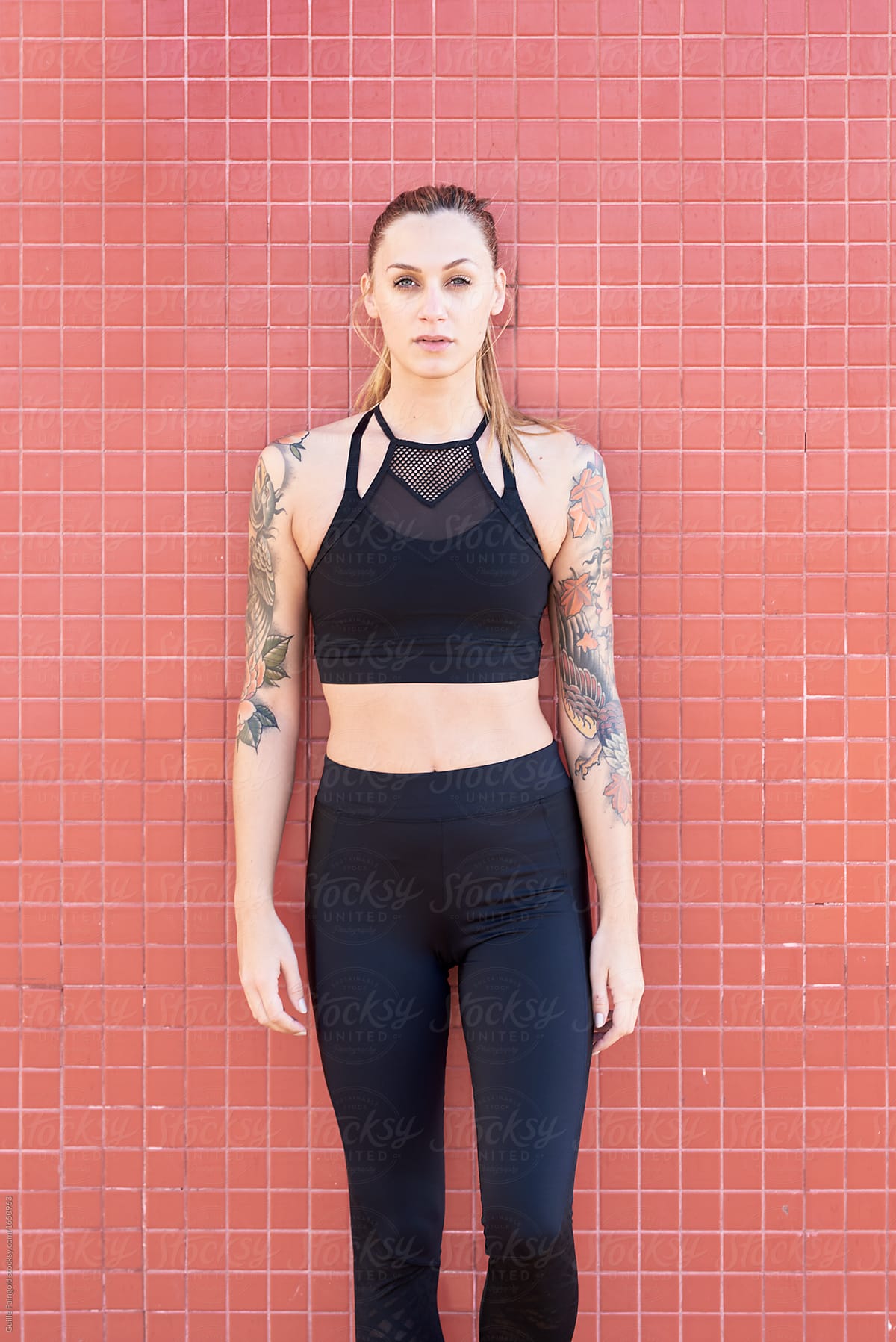 Woman in black sportswear with tattooed arms