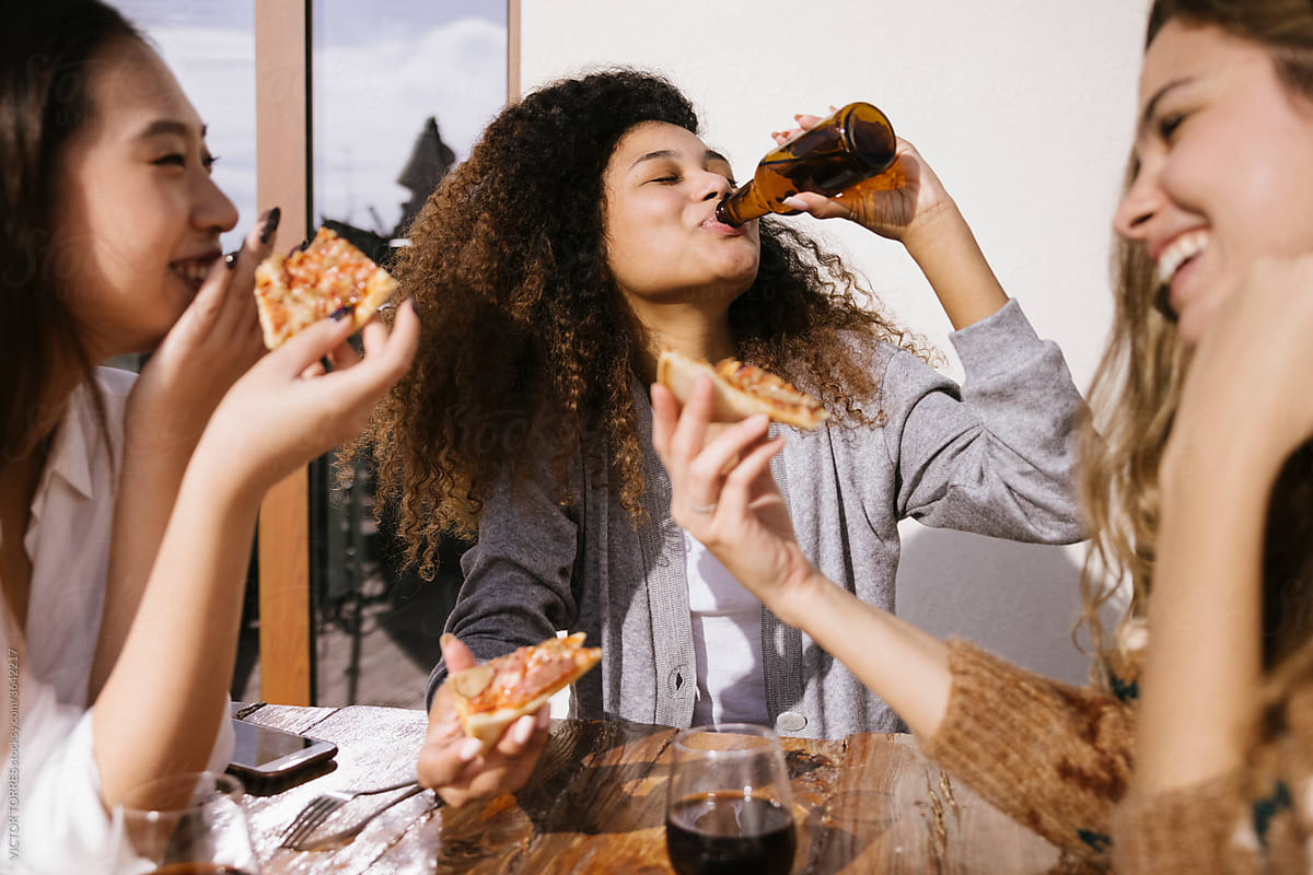 Company of diverse women eating pizza together