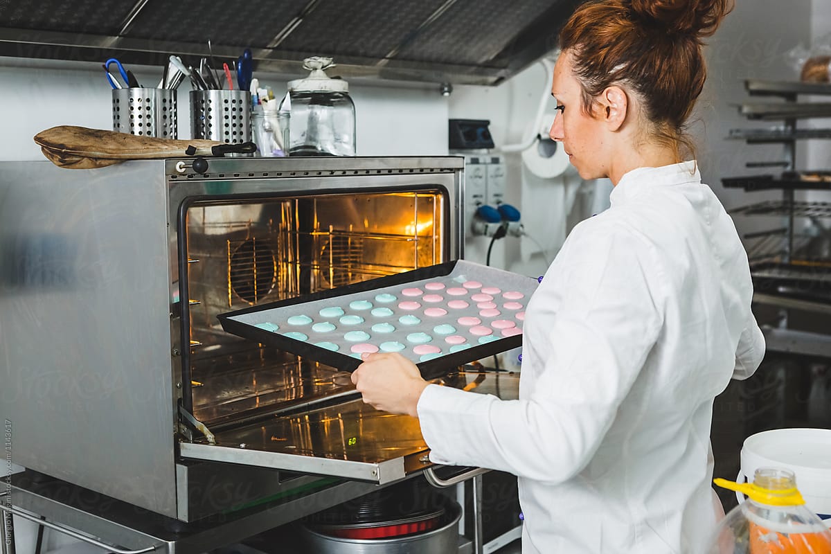 Pastry Chef Putting a Tray of Raw Macarons in the Oven of a Prof