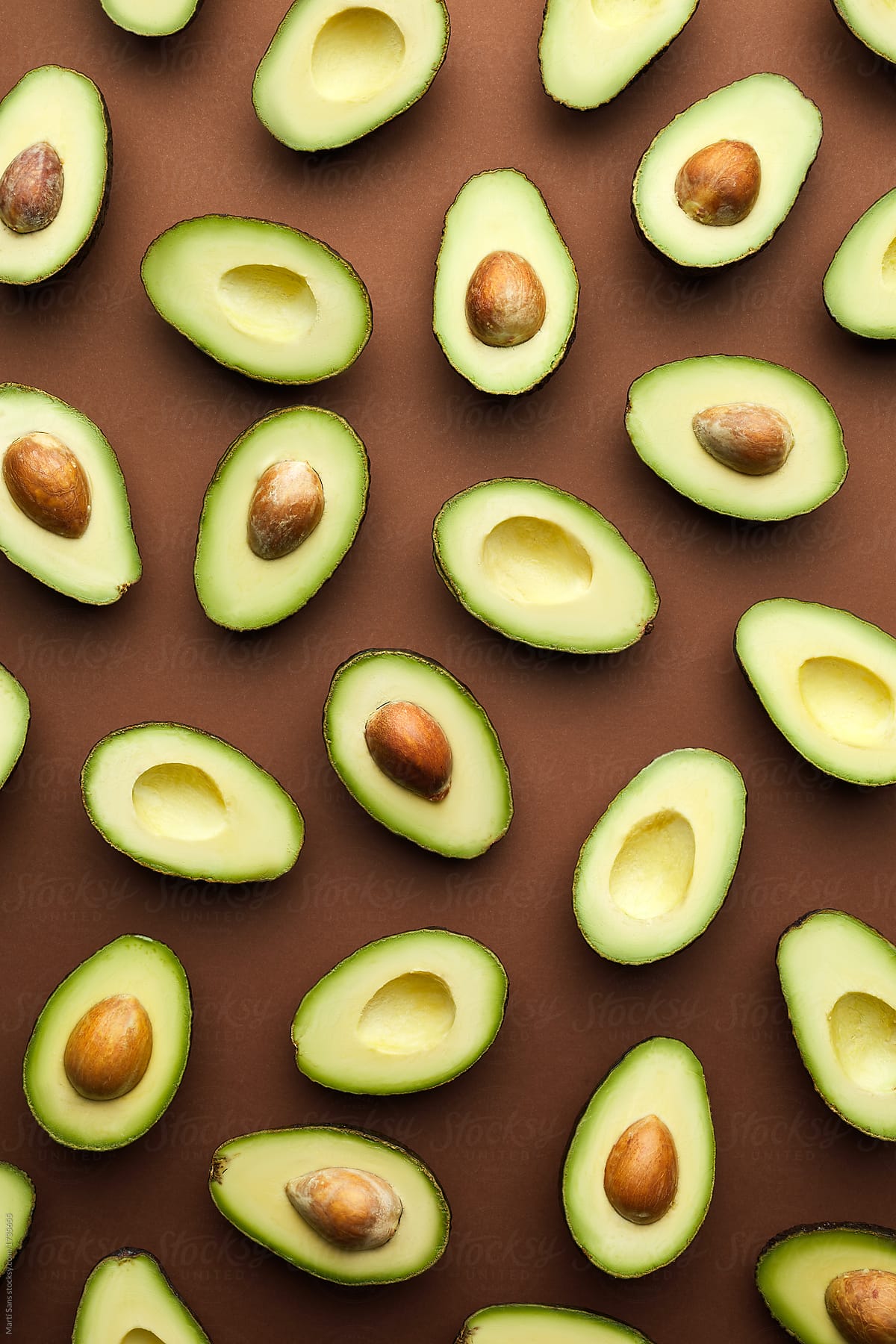 Halved avocados on brown.