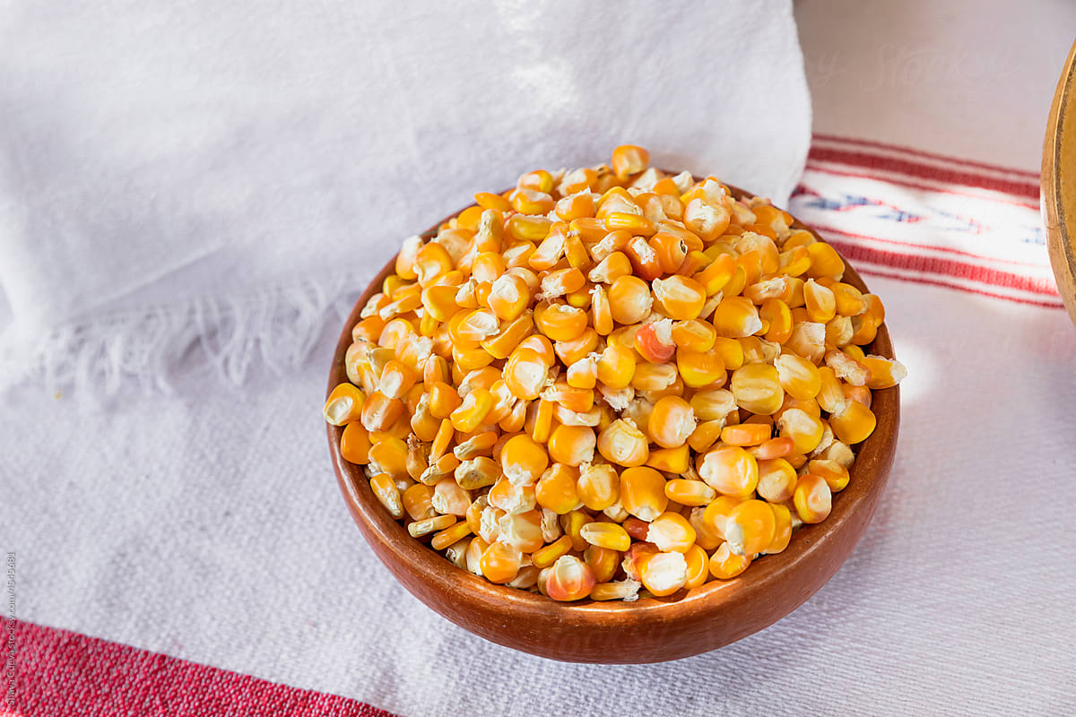 small clay bowl filled with uncooked yellow corn kernels