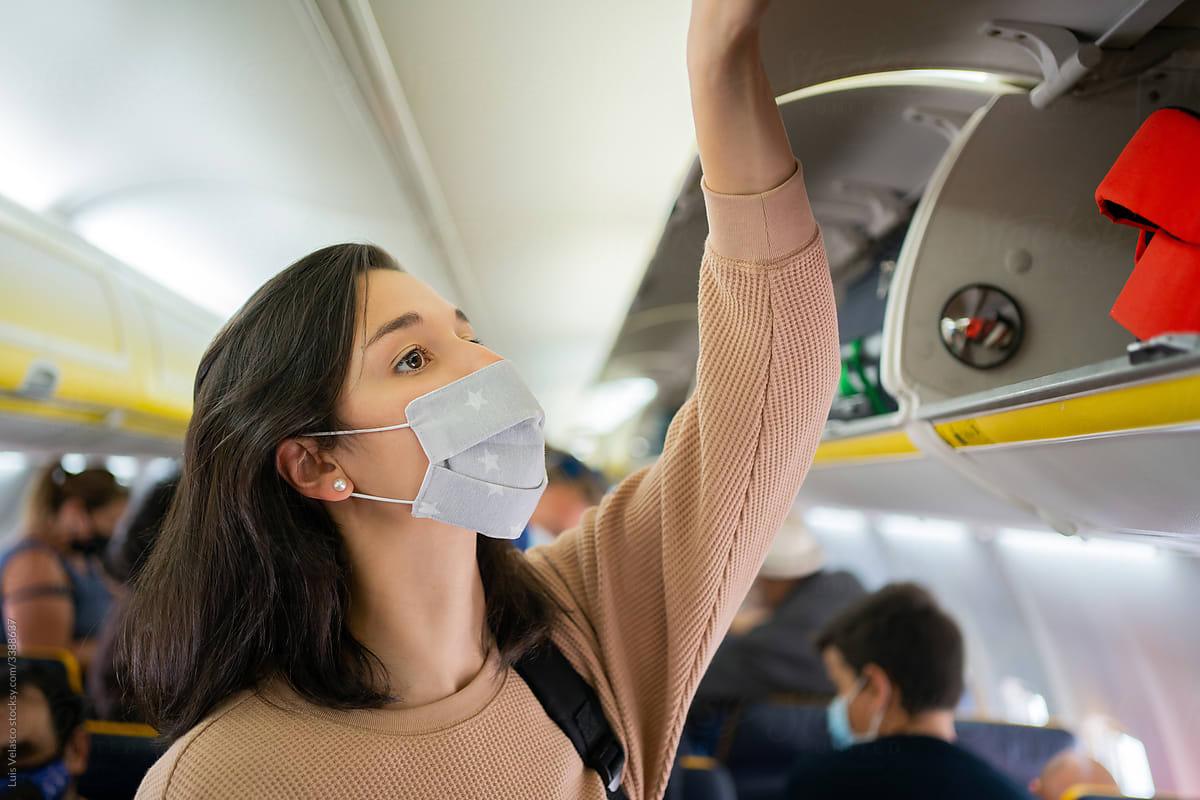 Woman With Mask Taking Her Luggage In A Plane.