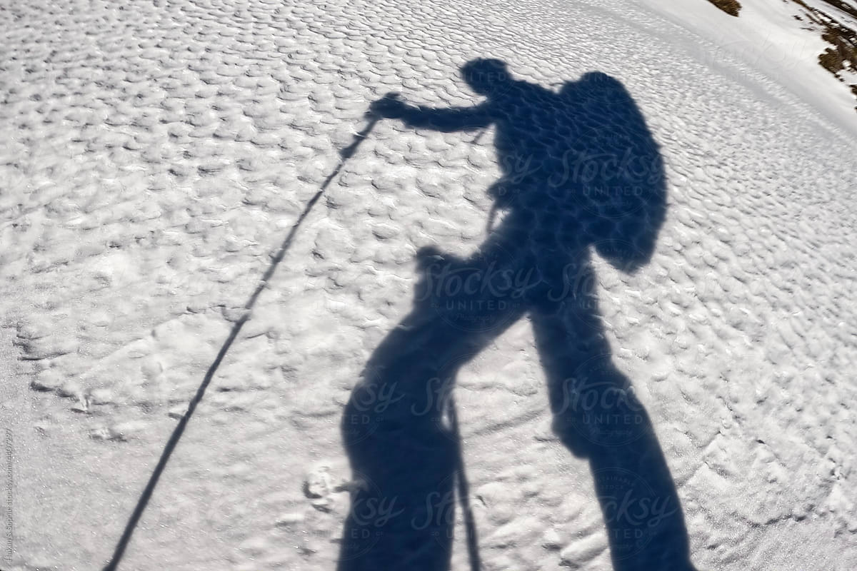shadow of man walking on snowy hill