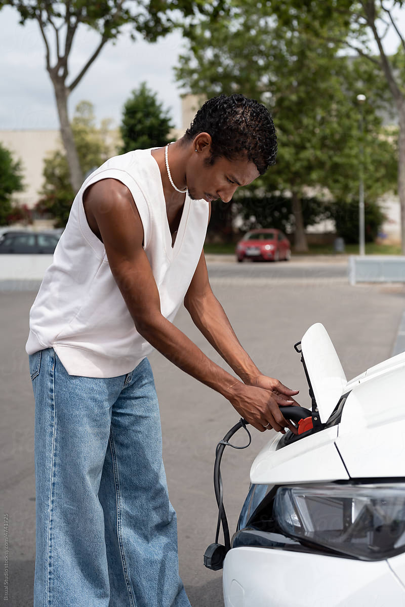 Young black man charging an electric car