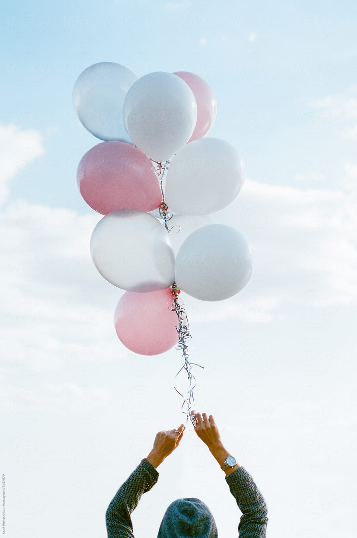 Person holding balloons high