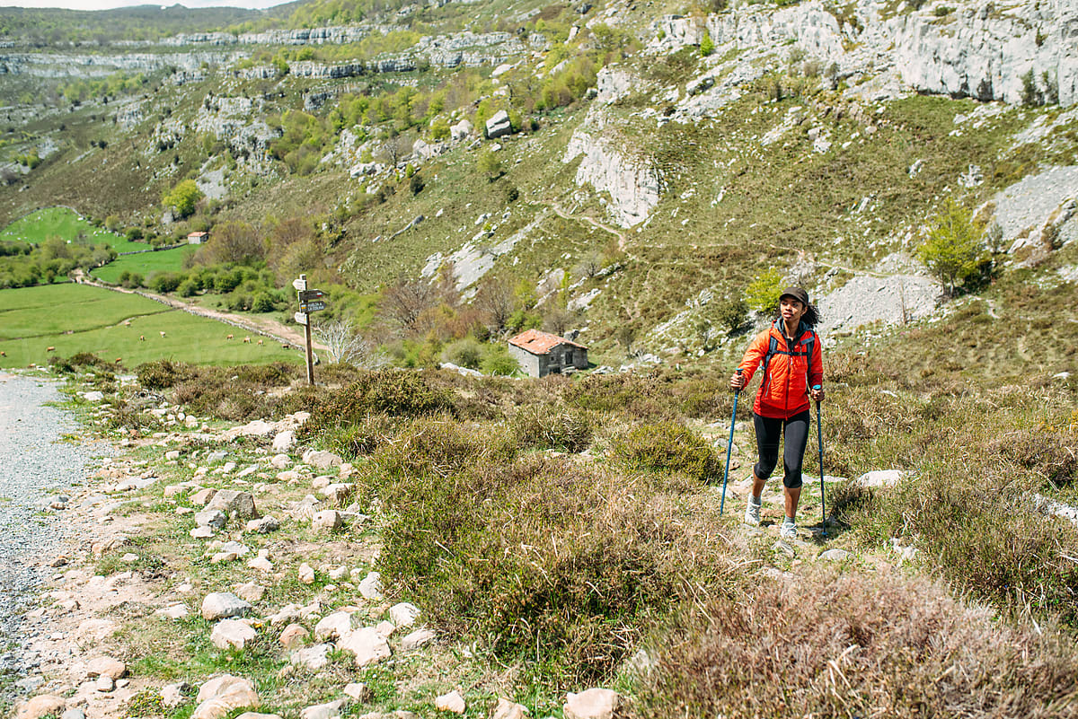 woman hiking with trekking poles in mountains