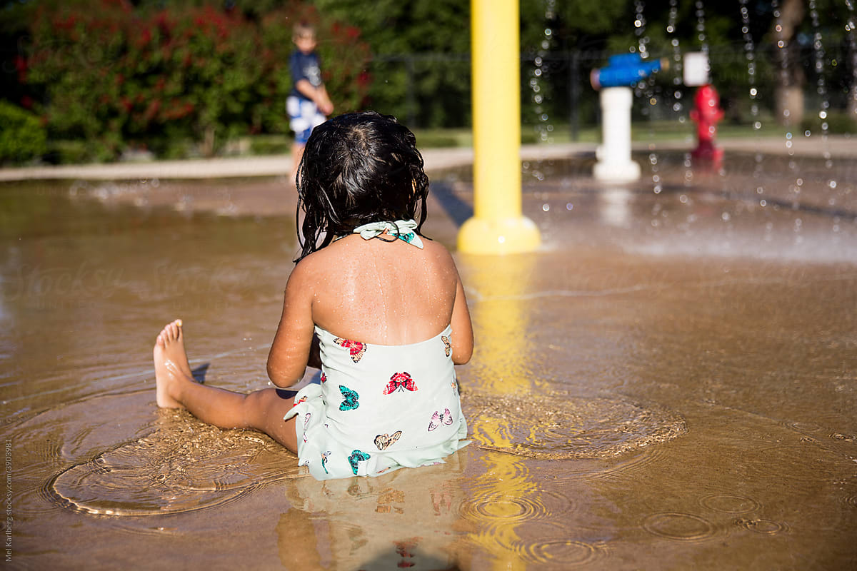 Girl in butterfly swimsuit at a splash pad
