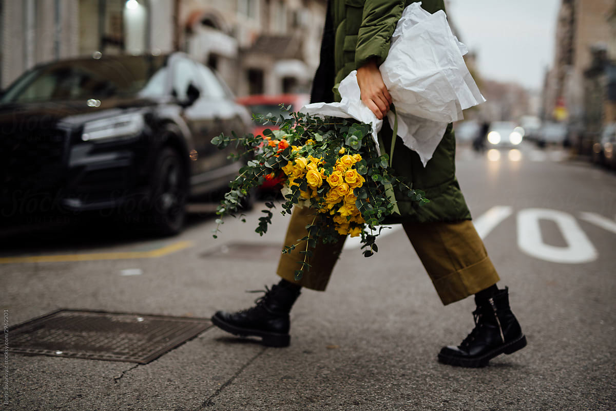 An Anonymous Girl Walking On An Empty City Street Holding A Bouquet