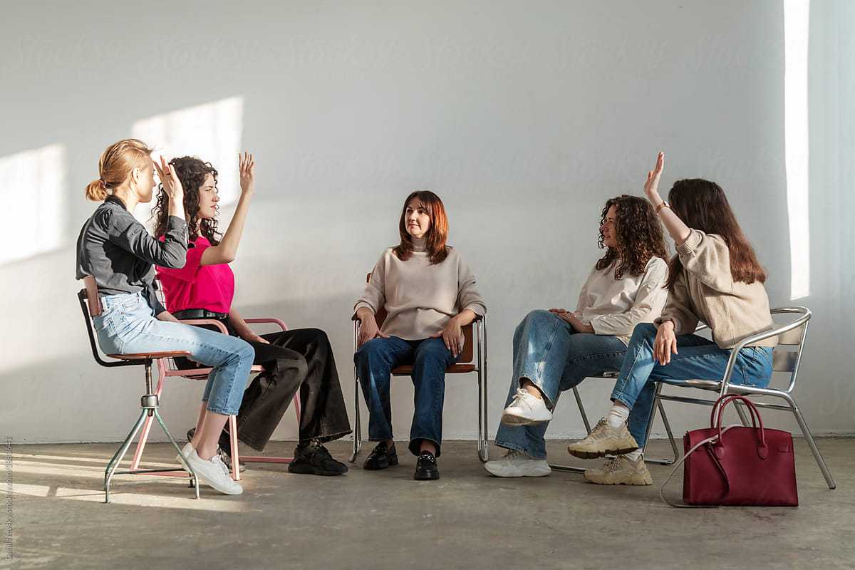 Group of young women siting on chair while having meeting together