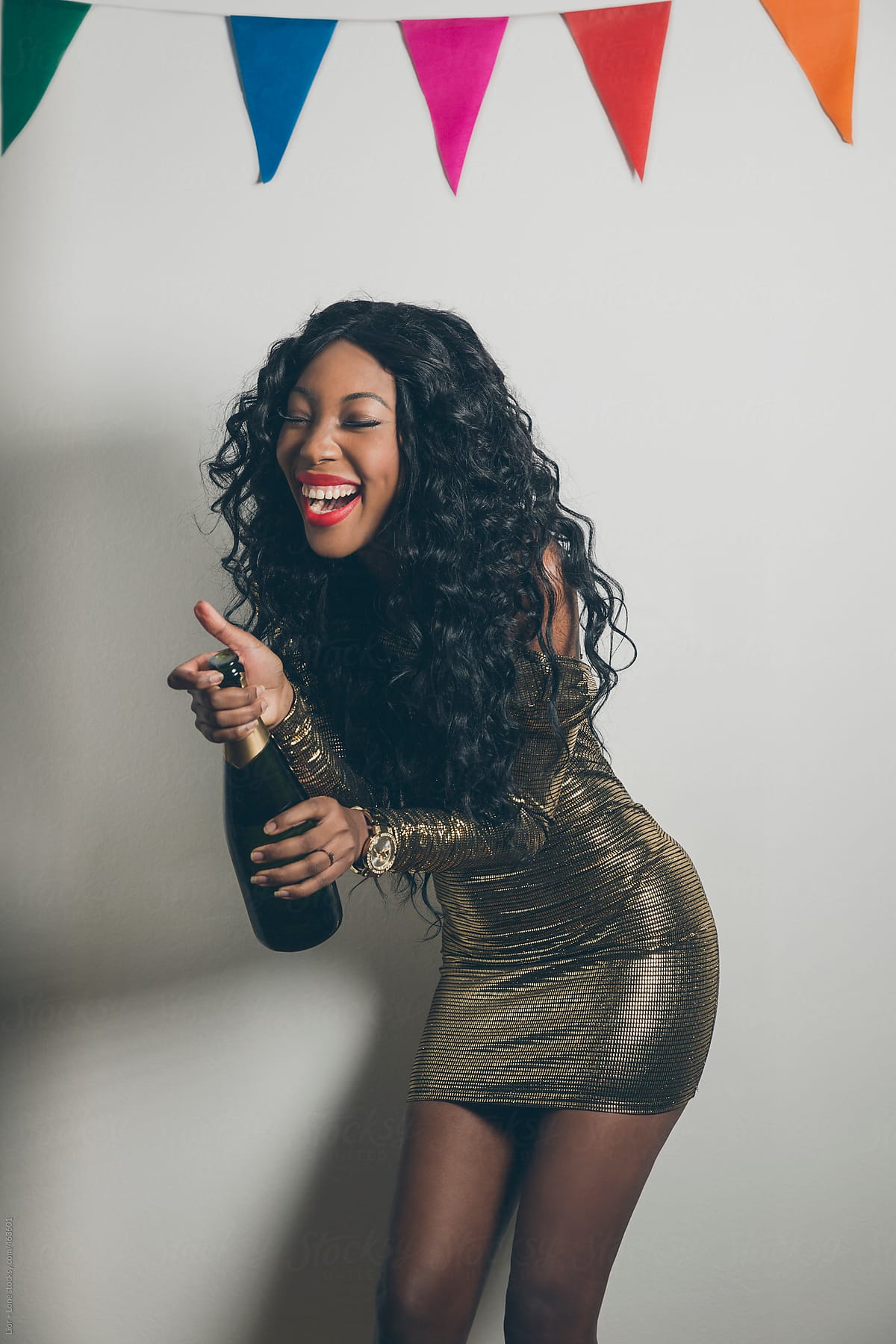 Black woman laughing while opening a champagne bottle at a party