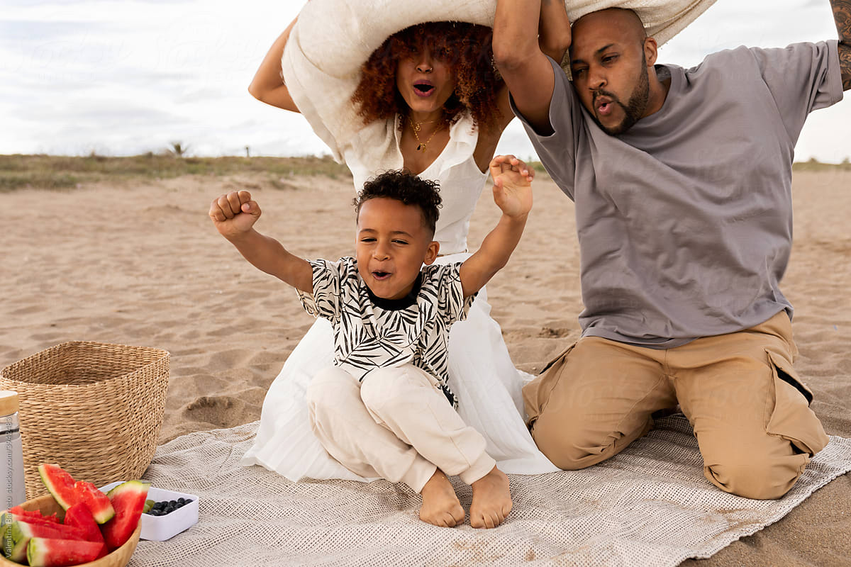 Happy family doing funny gesturing at beach picnic