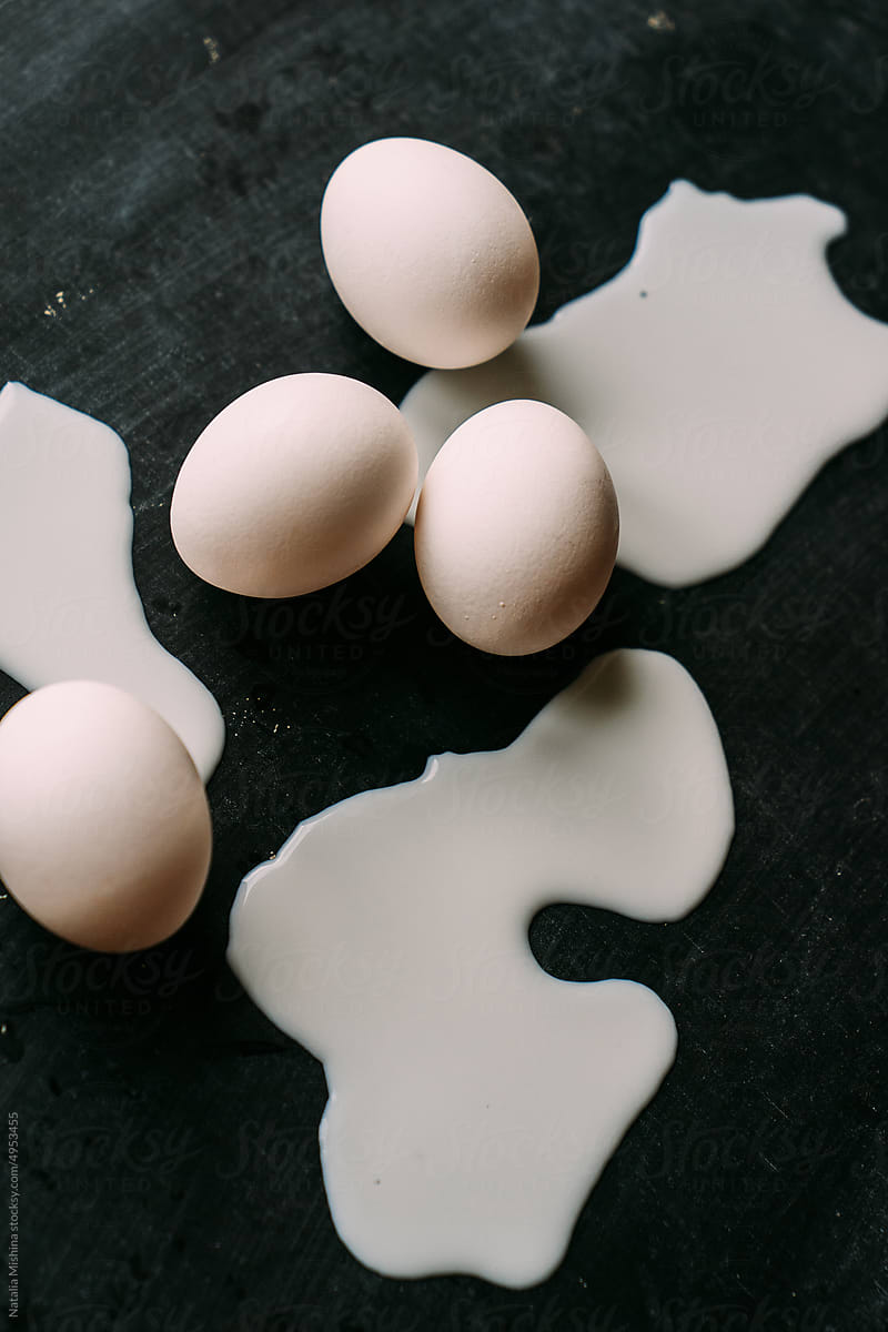 White raw eggs in spilled milk.