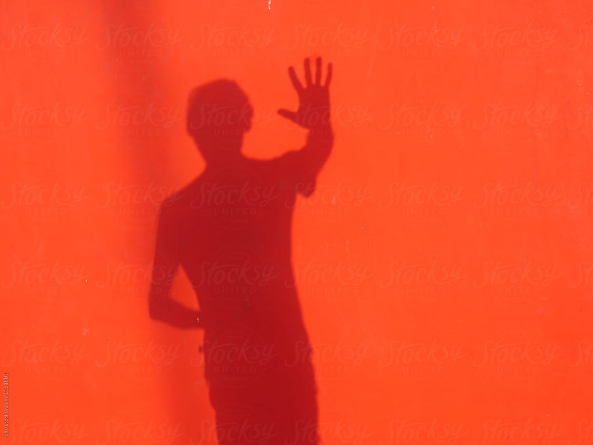Male shade on red wall with stop sign