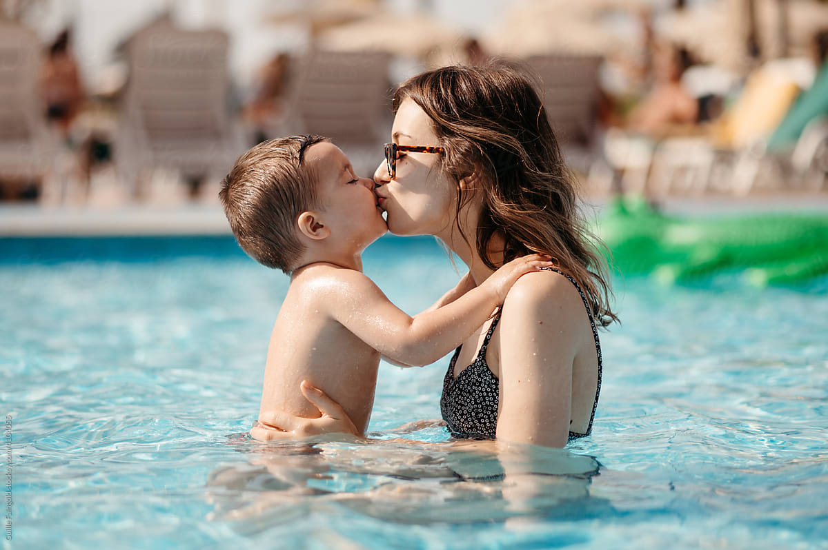 Mother kissing son in pool.