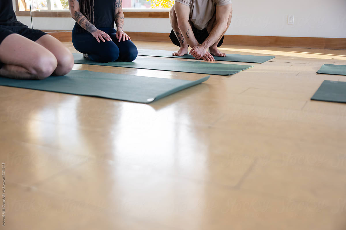 Group of people kneeling on yoga mats in studio class.
