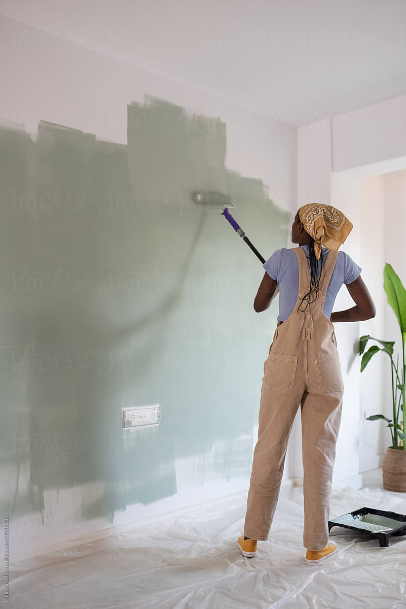 Black female painting wall in apartment