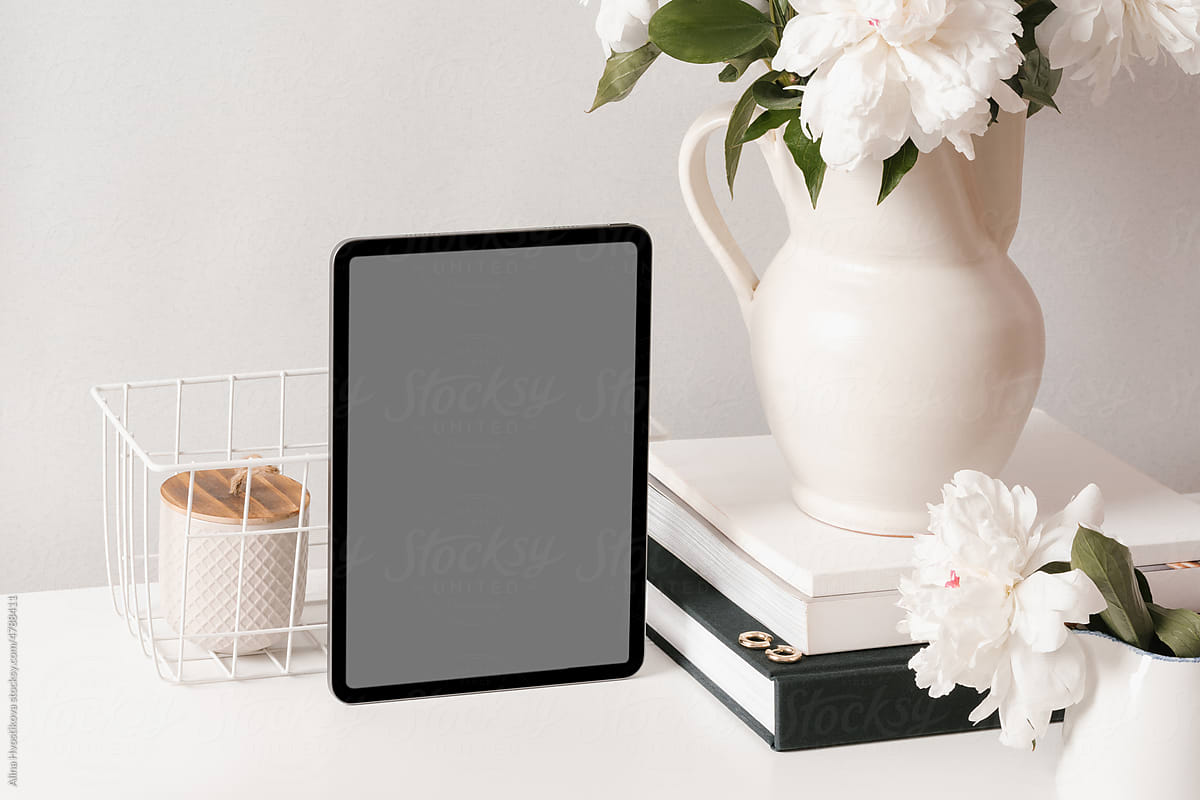 Tablet with decorative elements and books on table