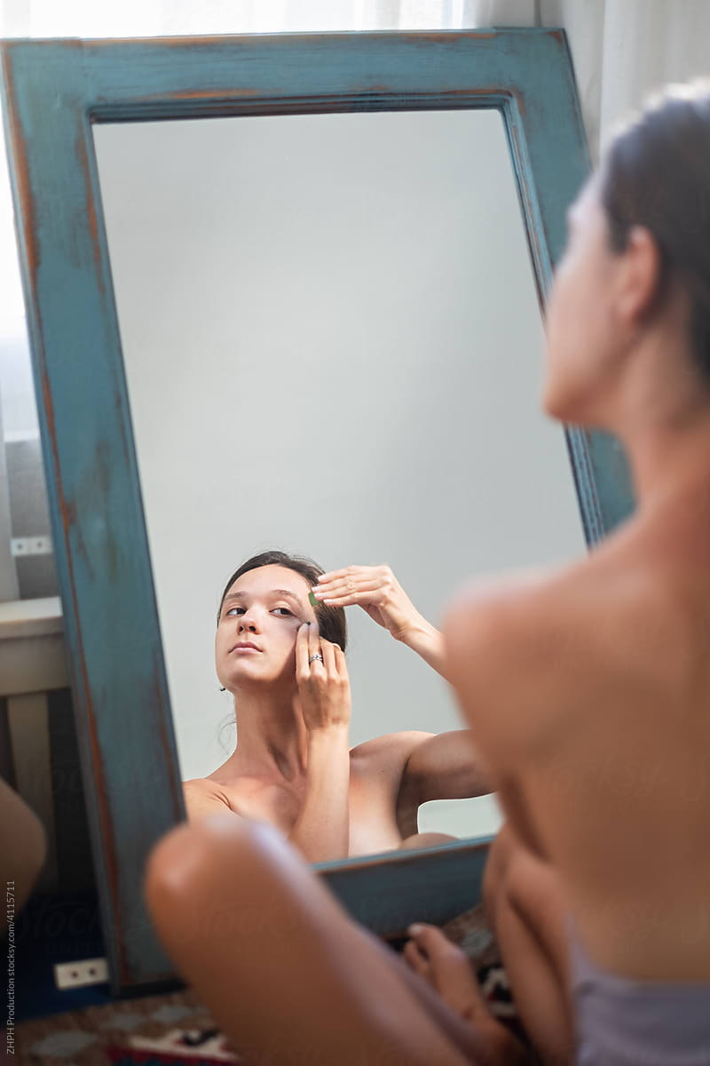 Young woman applying fresh aloe on face skin