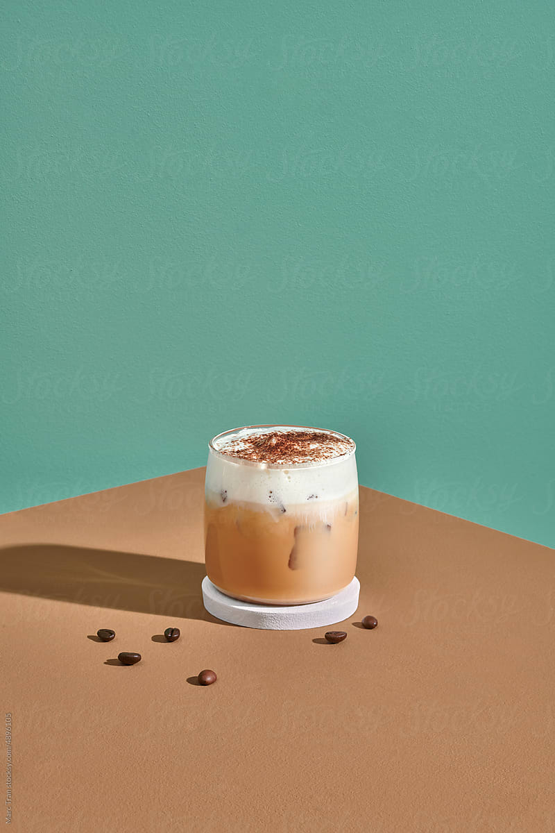 Iced coffee in a short glass with cream poured over iced cubes