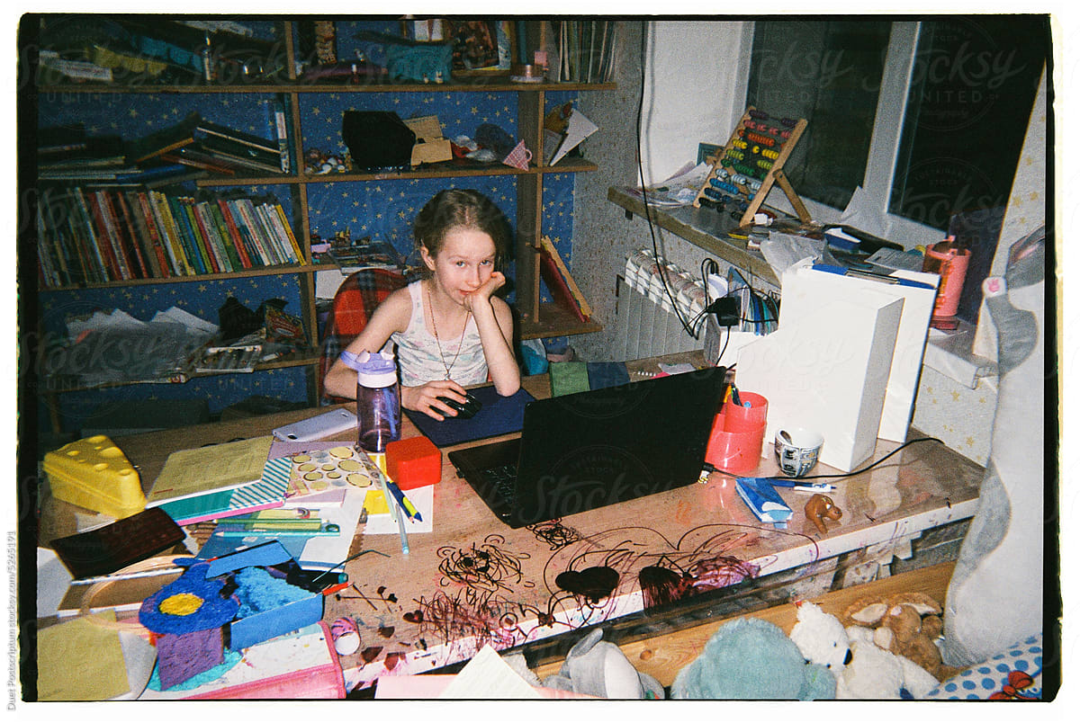 Blond girl doing homework on her laptop in a room