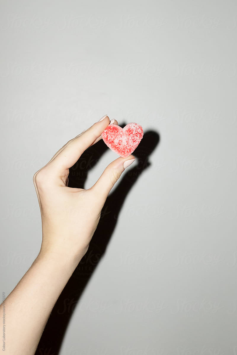 Hand holding red heart candy representing love with hard flashlight