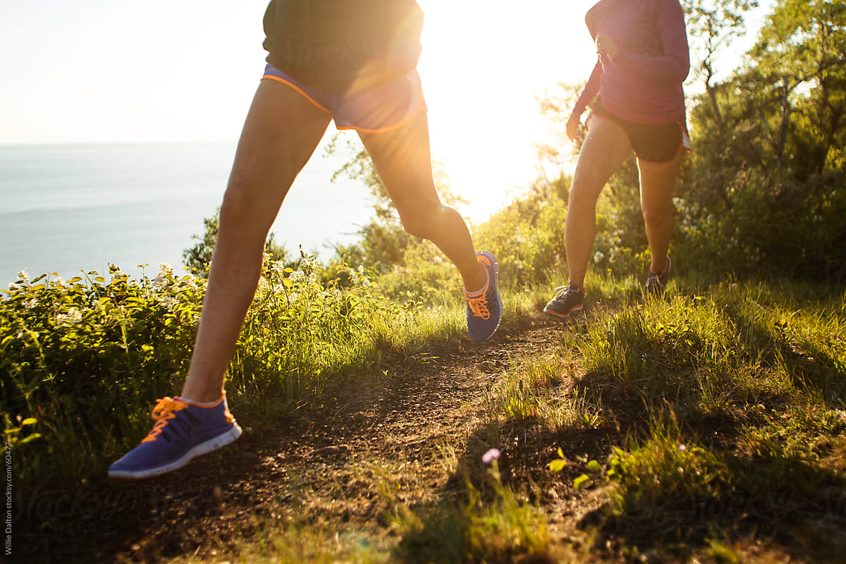 Two Women Run Along an Oceanside Trail During Sunset