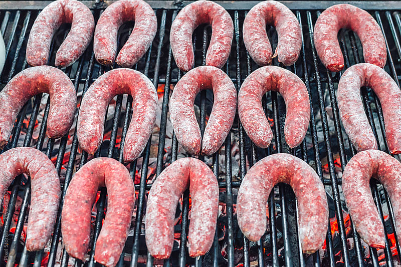 Raw sausages being grilled