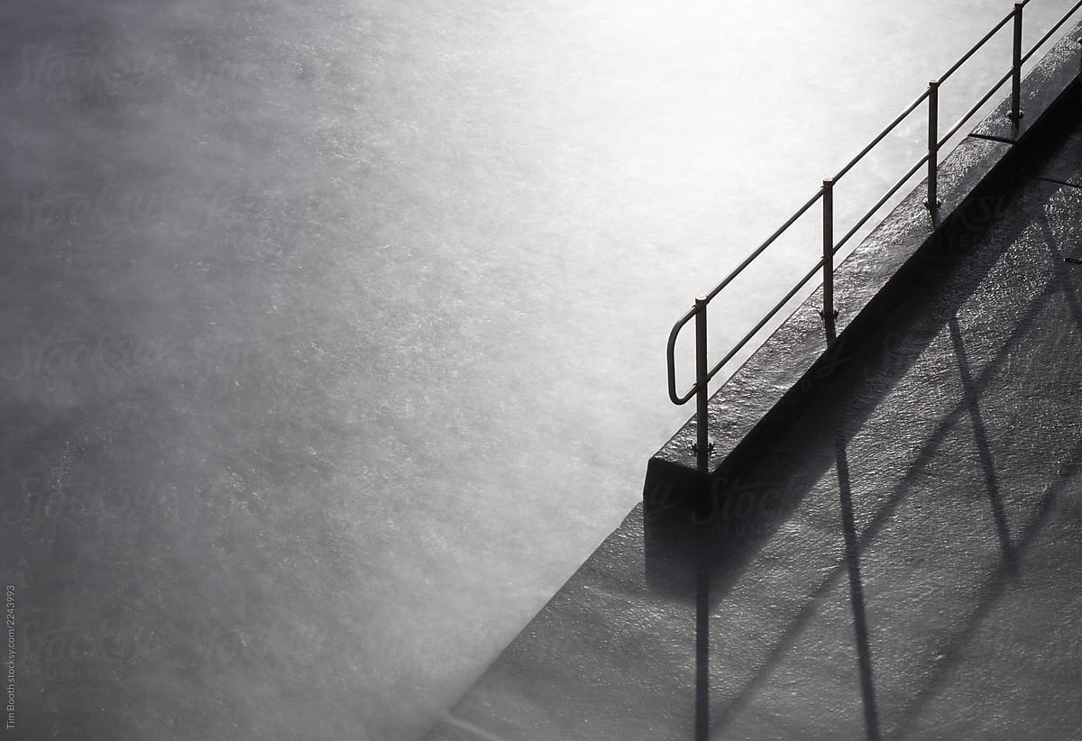 A steel handrail descending into misty water.