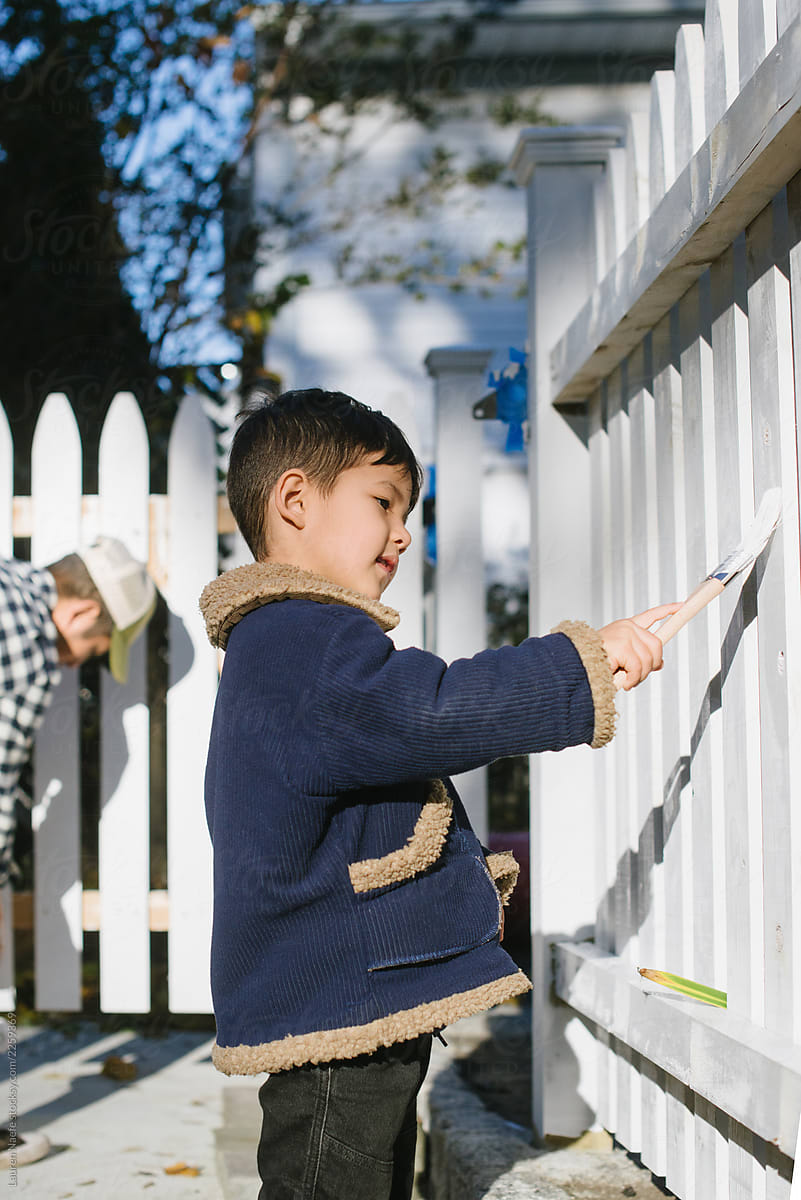 Little kid painting fence