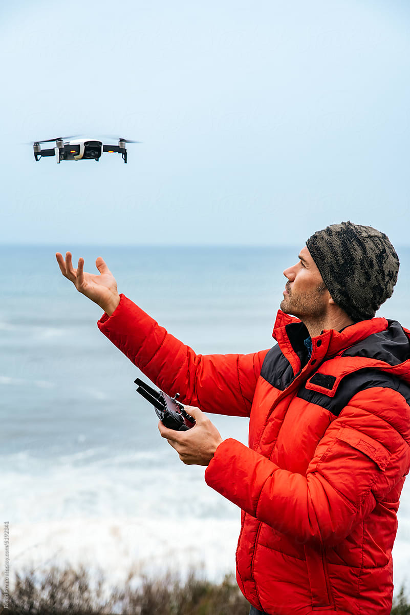 Male explorer operating drone near ocean