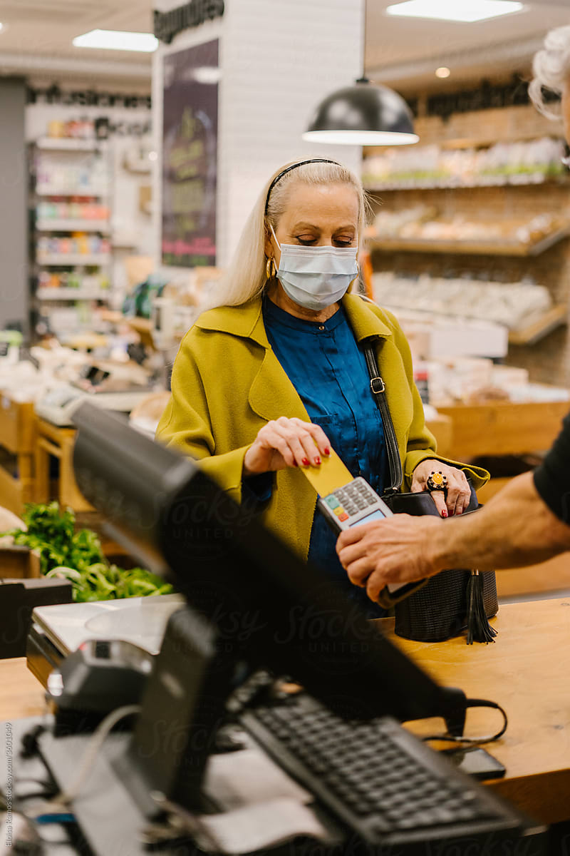 senior woman paying with card in a grocery store