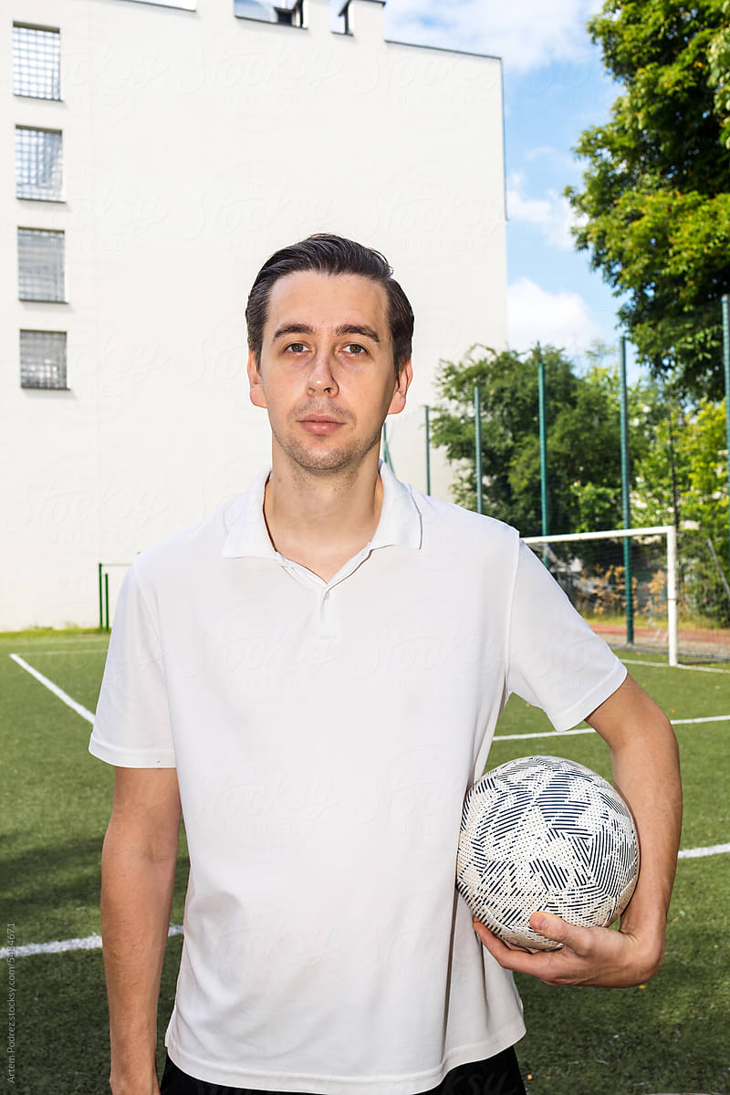man stands on a football field, holding a soccer ball. Before/After